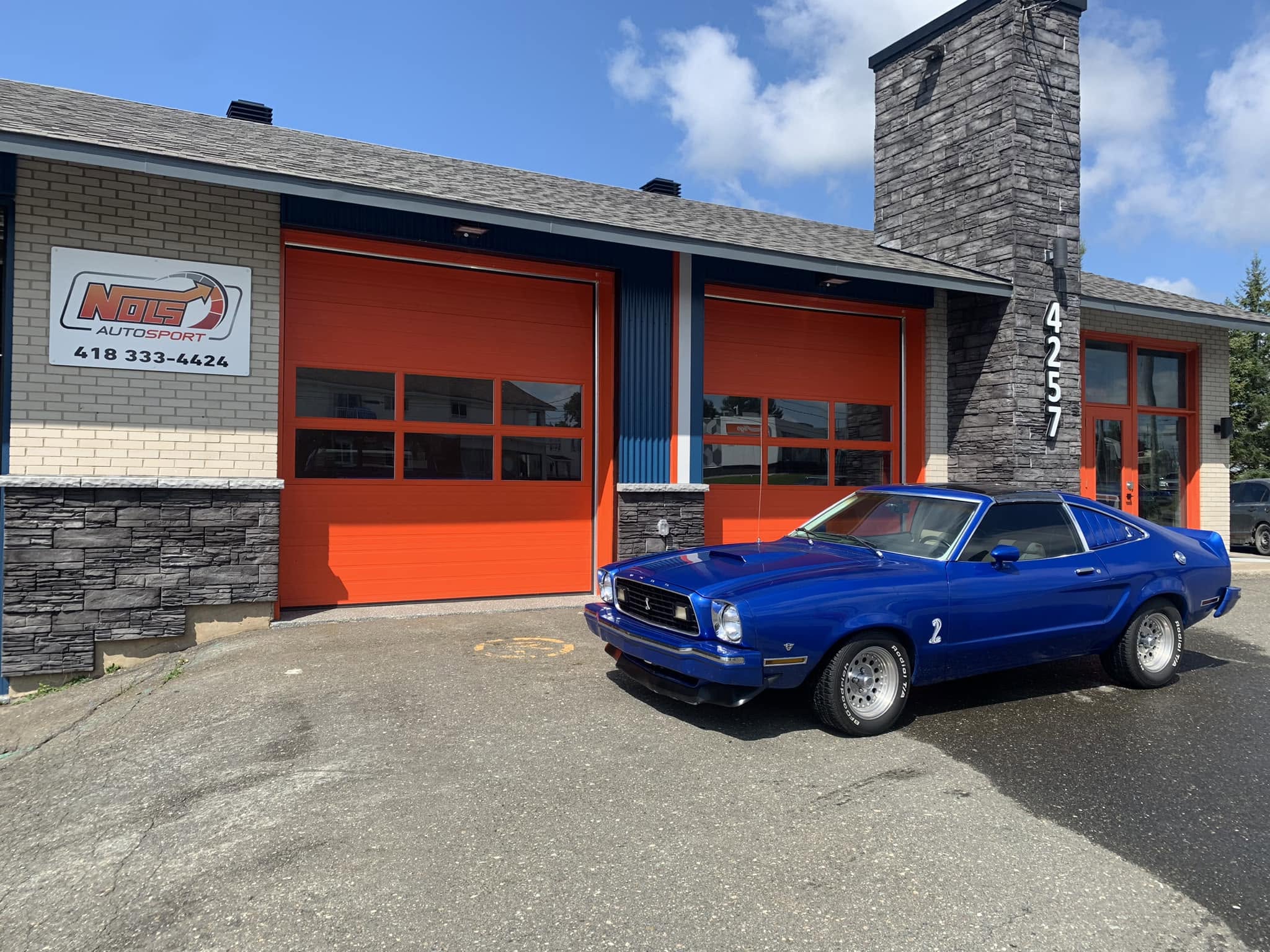 Ford Mustang bleue devant Nols Autosport